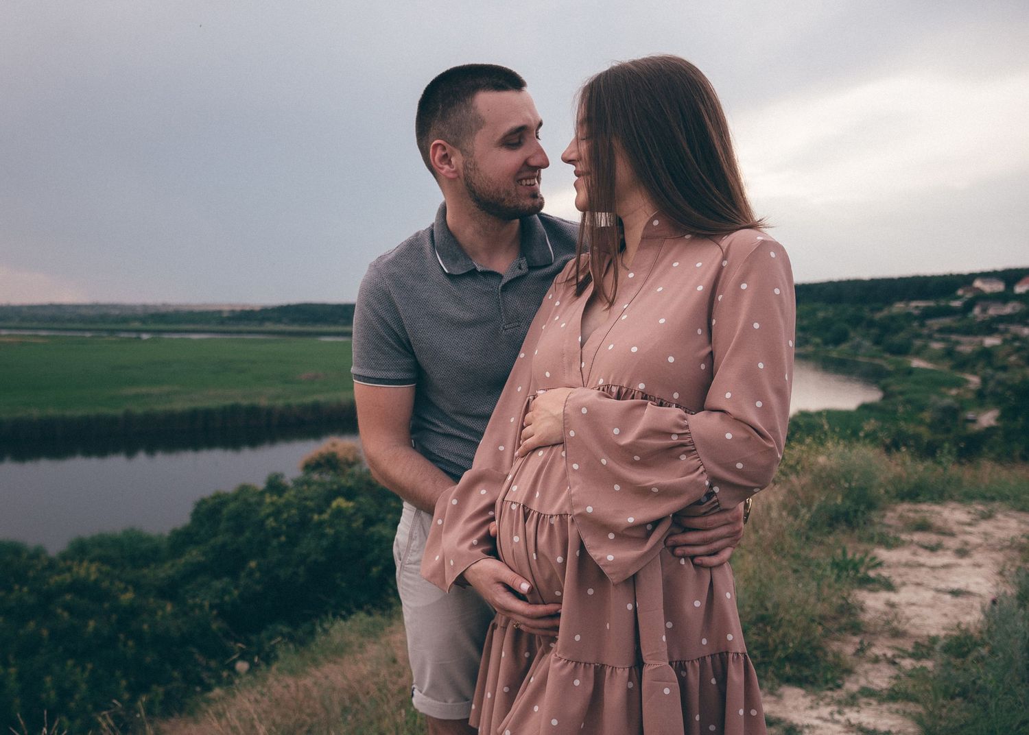 Couple attendant un enfant, moment tendre et complice lors d’une séance photo grossesse en lumière naturelle
