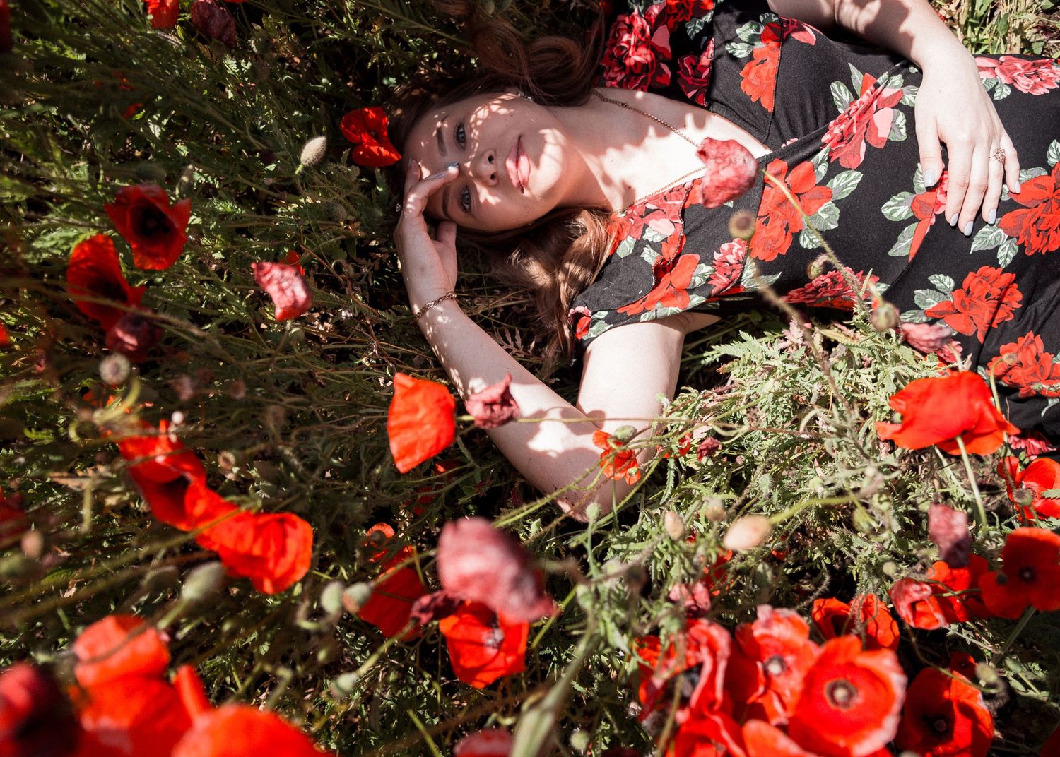 Femme enceinte allongée parmi des fleurs, séance photo grossesse artistique en extérieur
