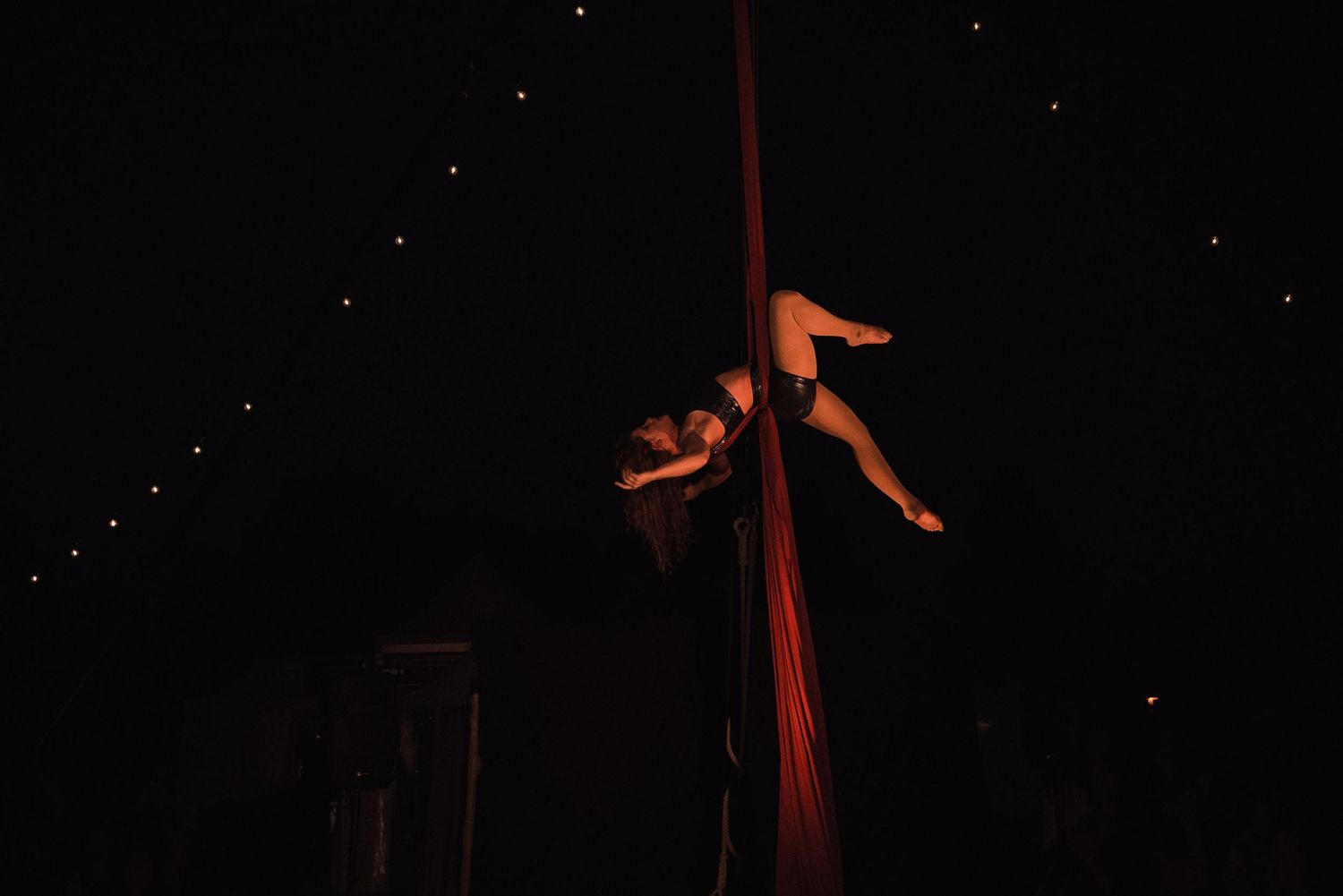 Performance de danse aérienne sur tissu, corps en mouvement dans une ambiance sombre et poétique