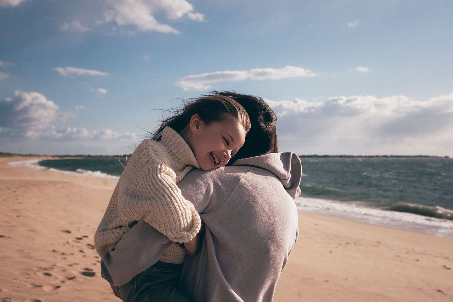 Câlin entre un parent et son enfant sur la plage de La Turballe, photographie familiale en lumière naturelle