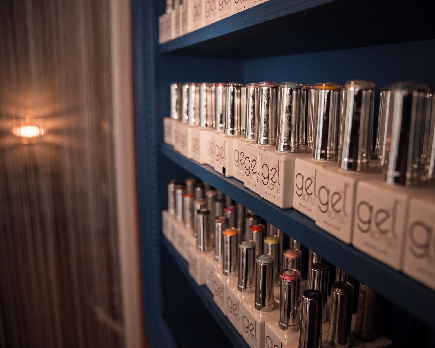 Vernis à ongles alignés sur des étagères, palette de couleurs et ambiance chaleureuse dans un salon à Saint-Nazaire