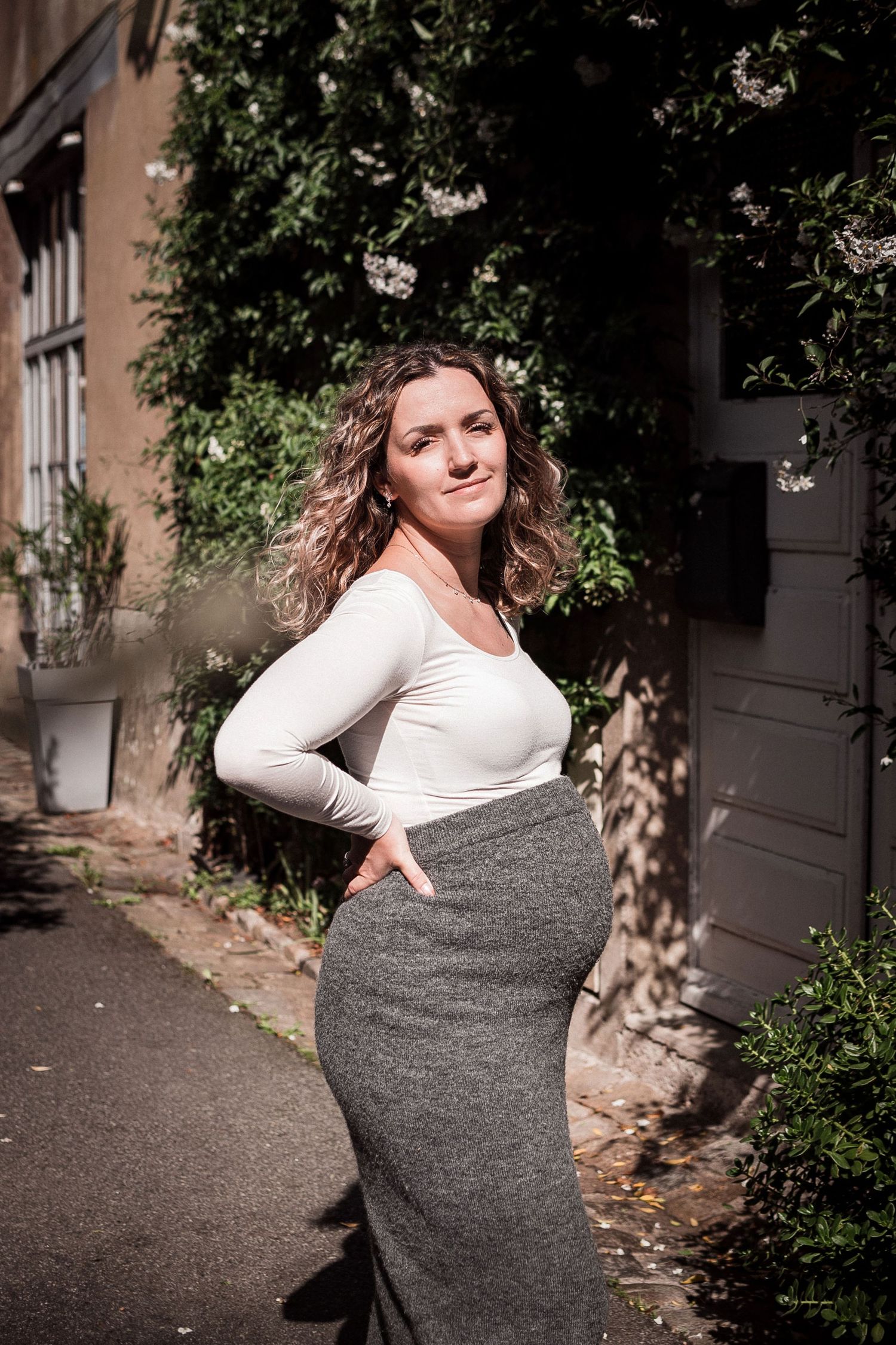 Portrait de femme enceinte en extérieur, pose naturelle et lumière douce dans une rue de Guérande