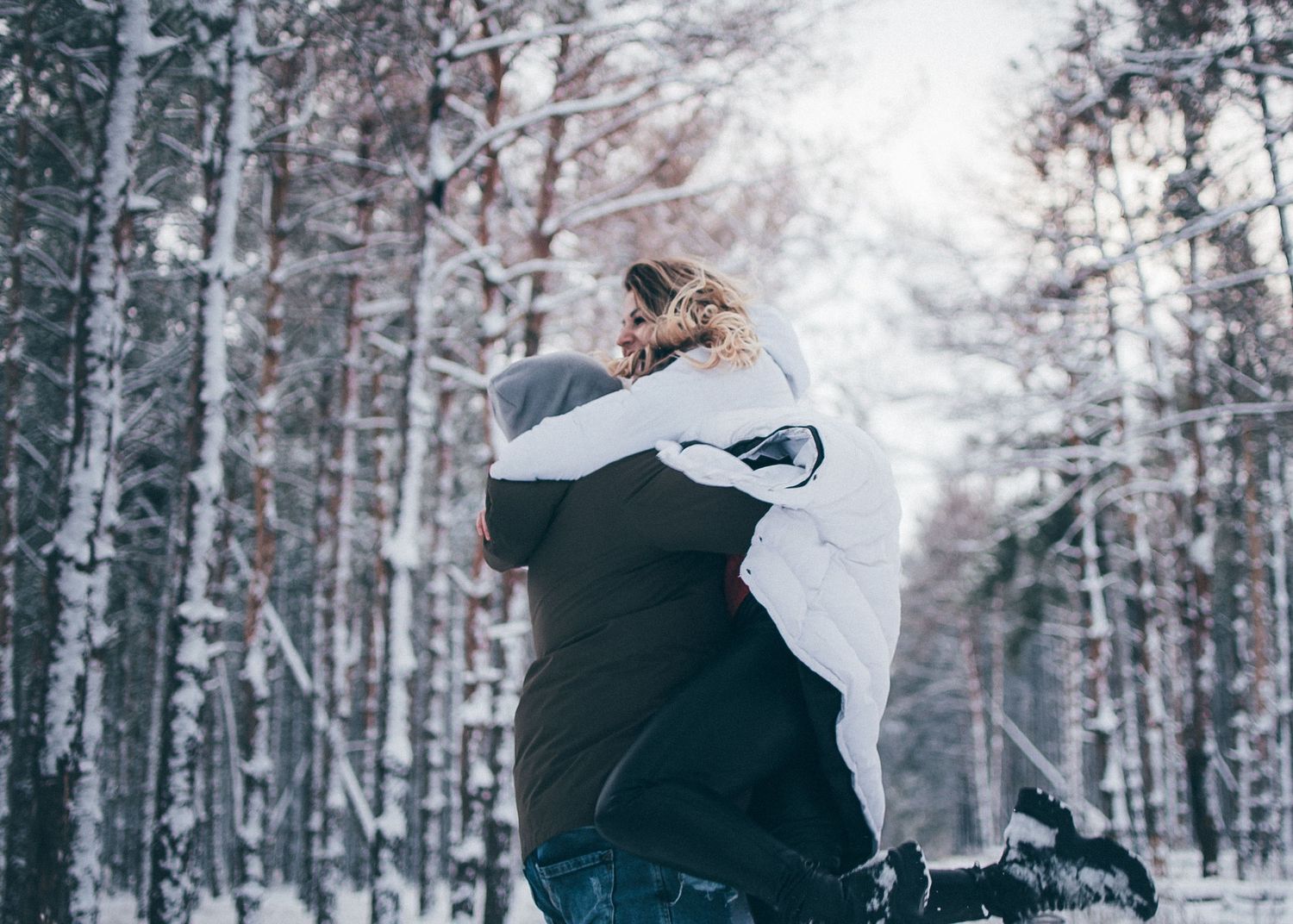 Playful winter scene with couple having fun in snowy forest.