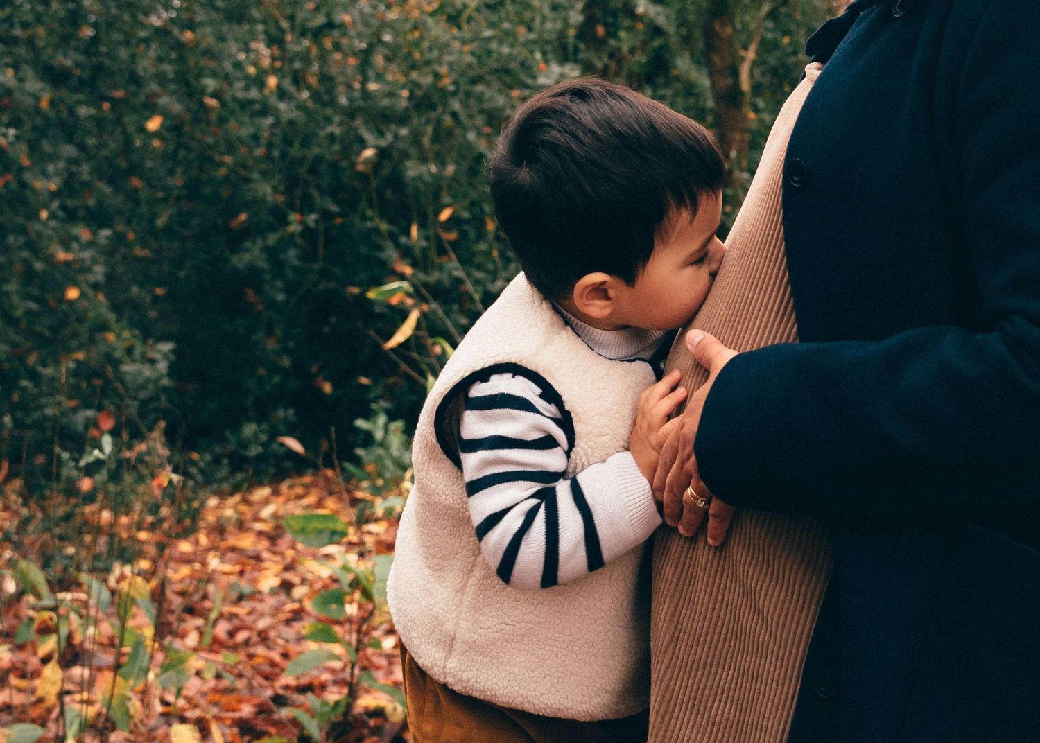 Enfant embrassant le ventre de sa maman enceinte, scène familiale émouvante au parc de la Chantrerie à Nantes