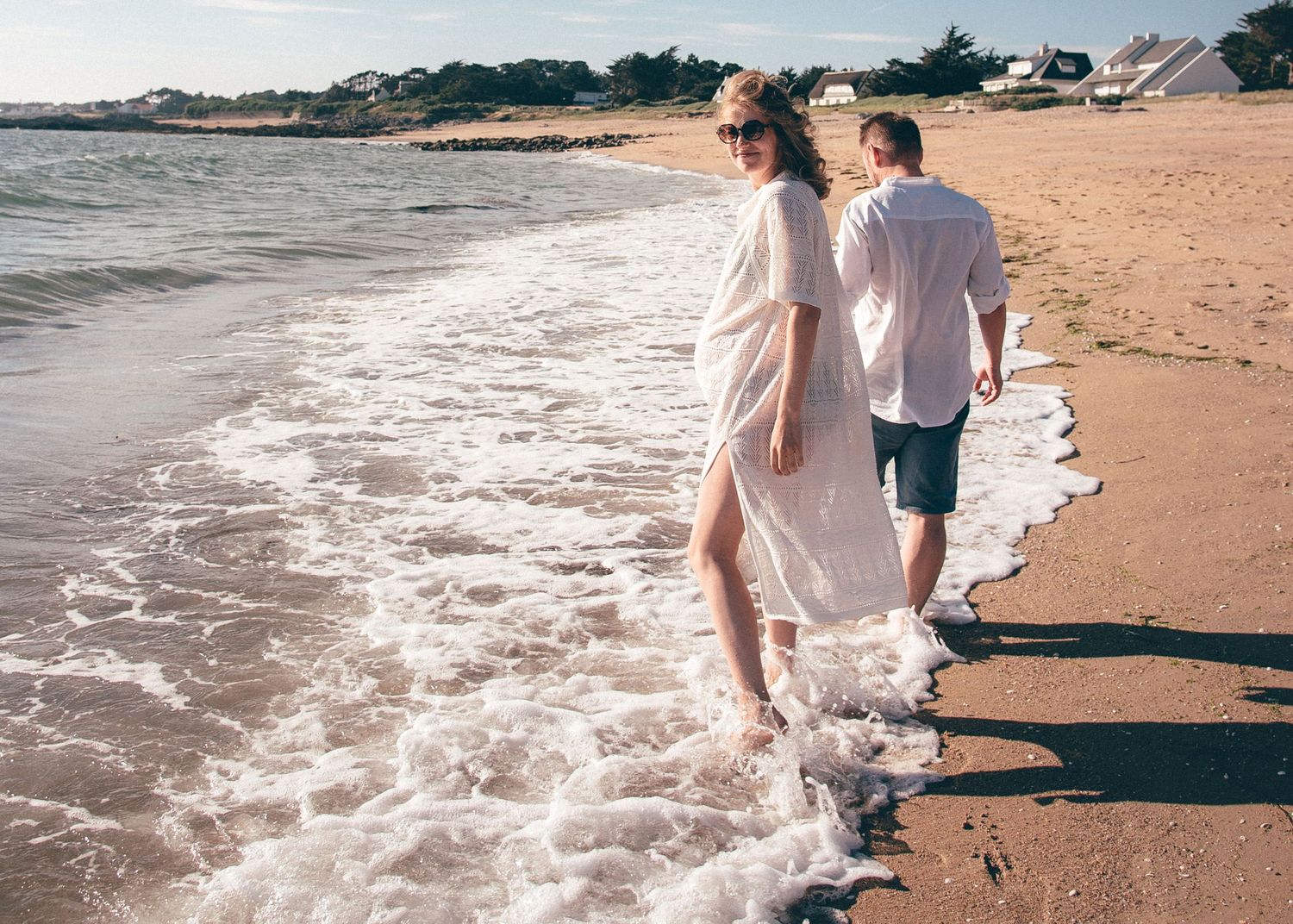 Couple marchant au bord de l’eau lors d’une séance photo grossesse sur la plage de La Turballe
