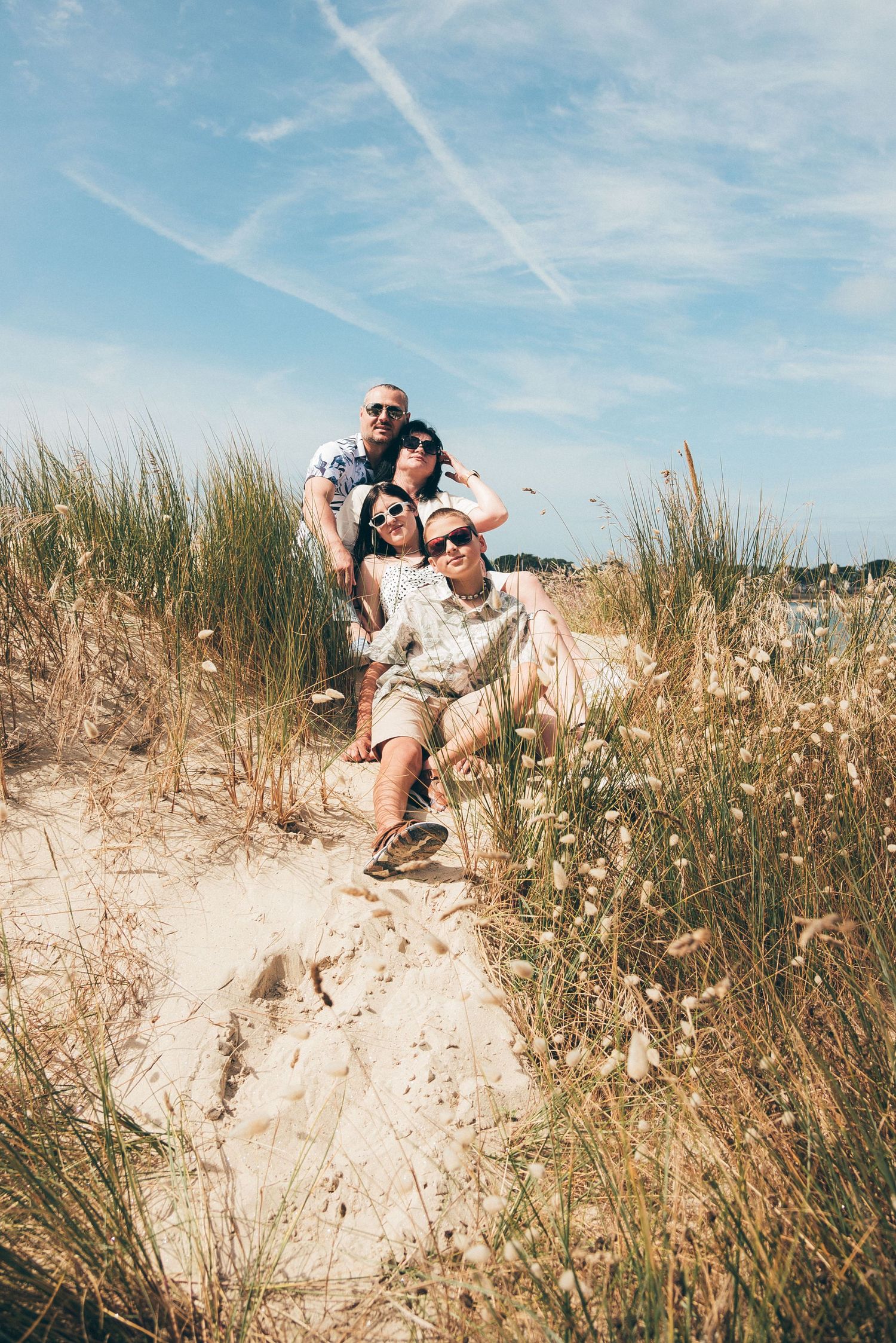 Famille assise dans les dunes de Pen Bron, séance photo lifestyle en lumière naturelle en Loire-Atlantique