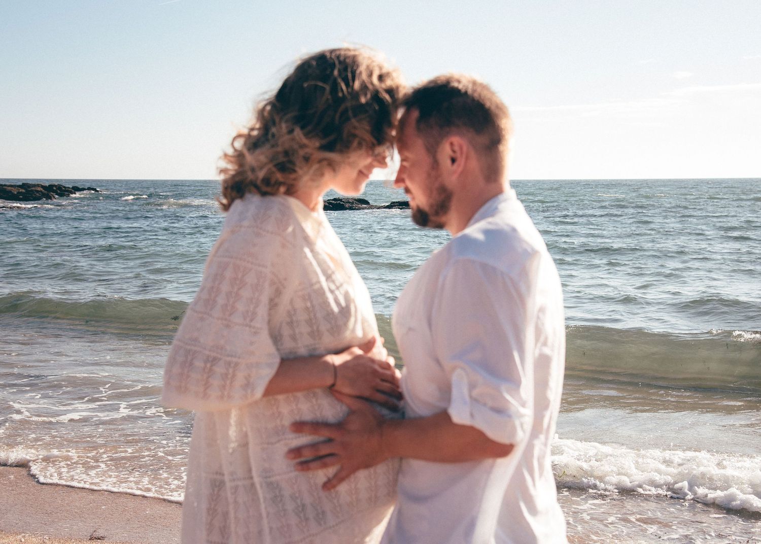 Couple attendant un enfant se faisant face au bord de l’océan, photographie de grossesse naturelle à La Turballe