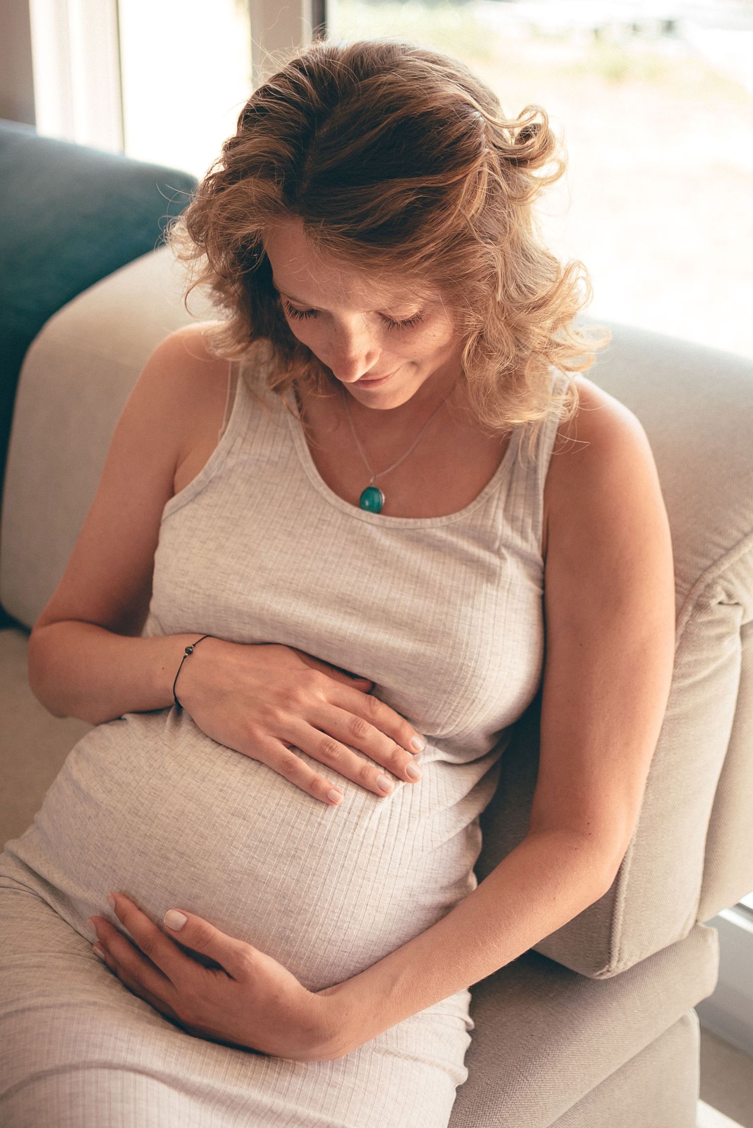 Femme enceinte assise dans un intérieur lumineux, moment de douceur et de connexion à La Turballe