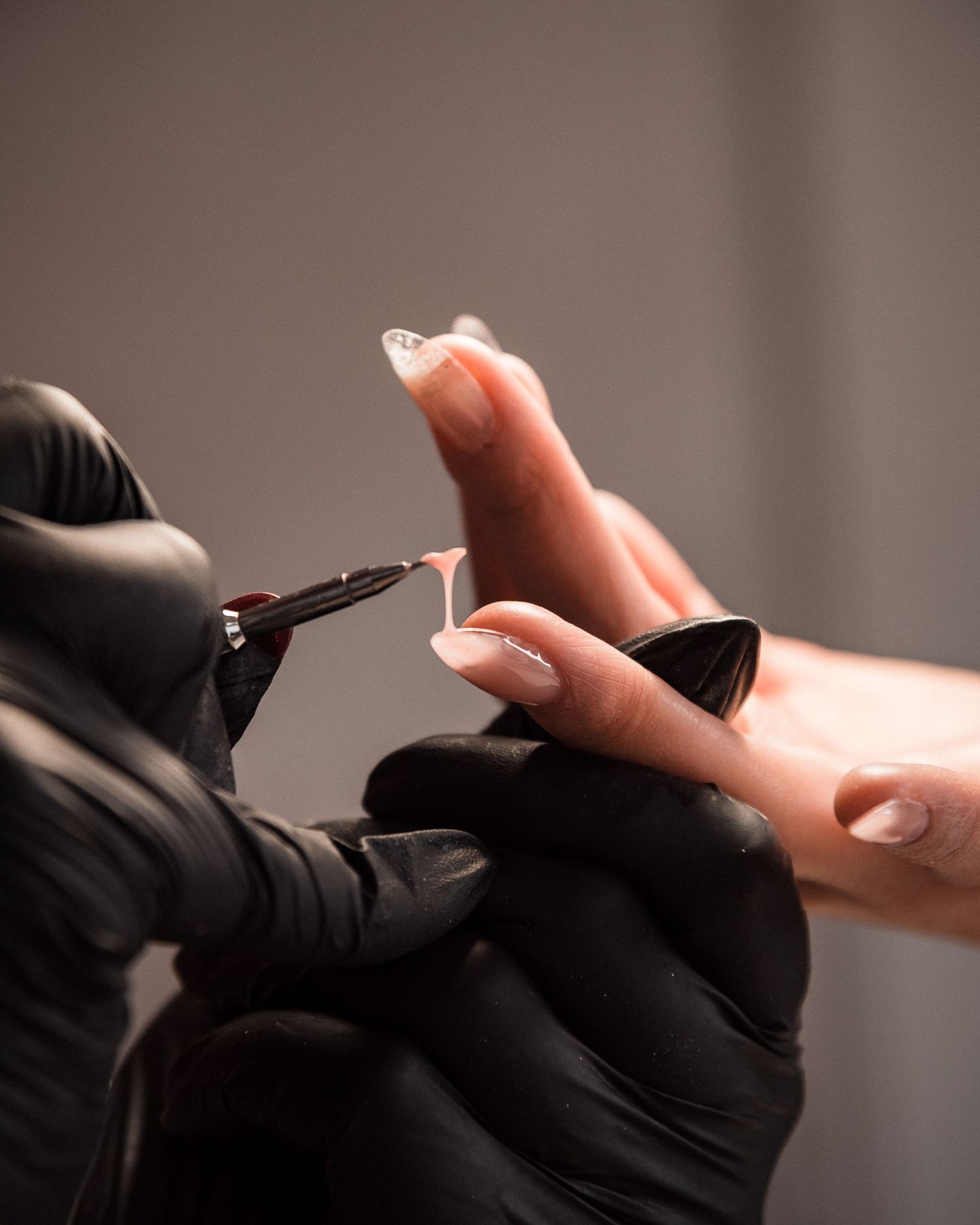 Pose de vernis en cours, geste précis d’une professionnelle de l’onglerie dans une ambiance douce à Guérande