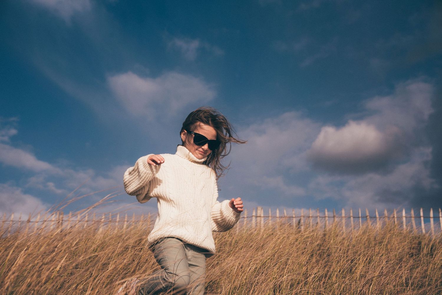 Enfant courant dans les dunes de La Turballe sous un ciel dramatique, photo naturelle en extérieur