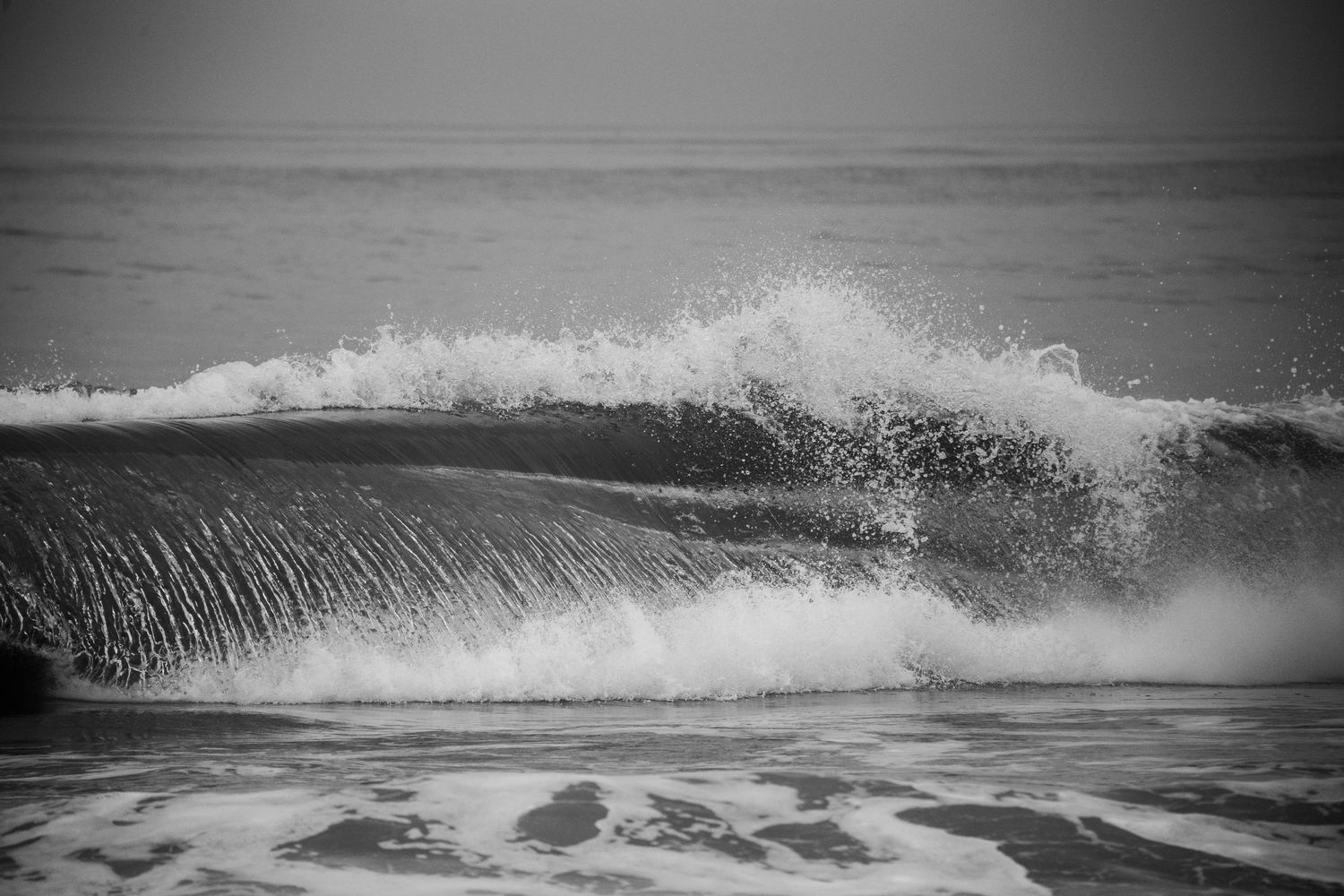 A sequence of black and white photographs showing ocean waves crashing and breaking along a shoreline.