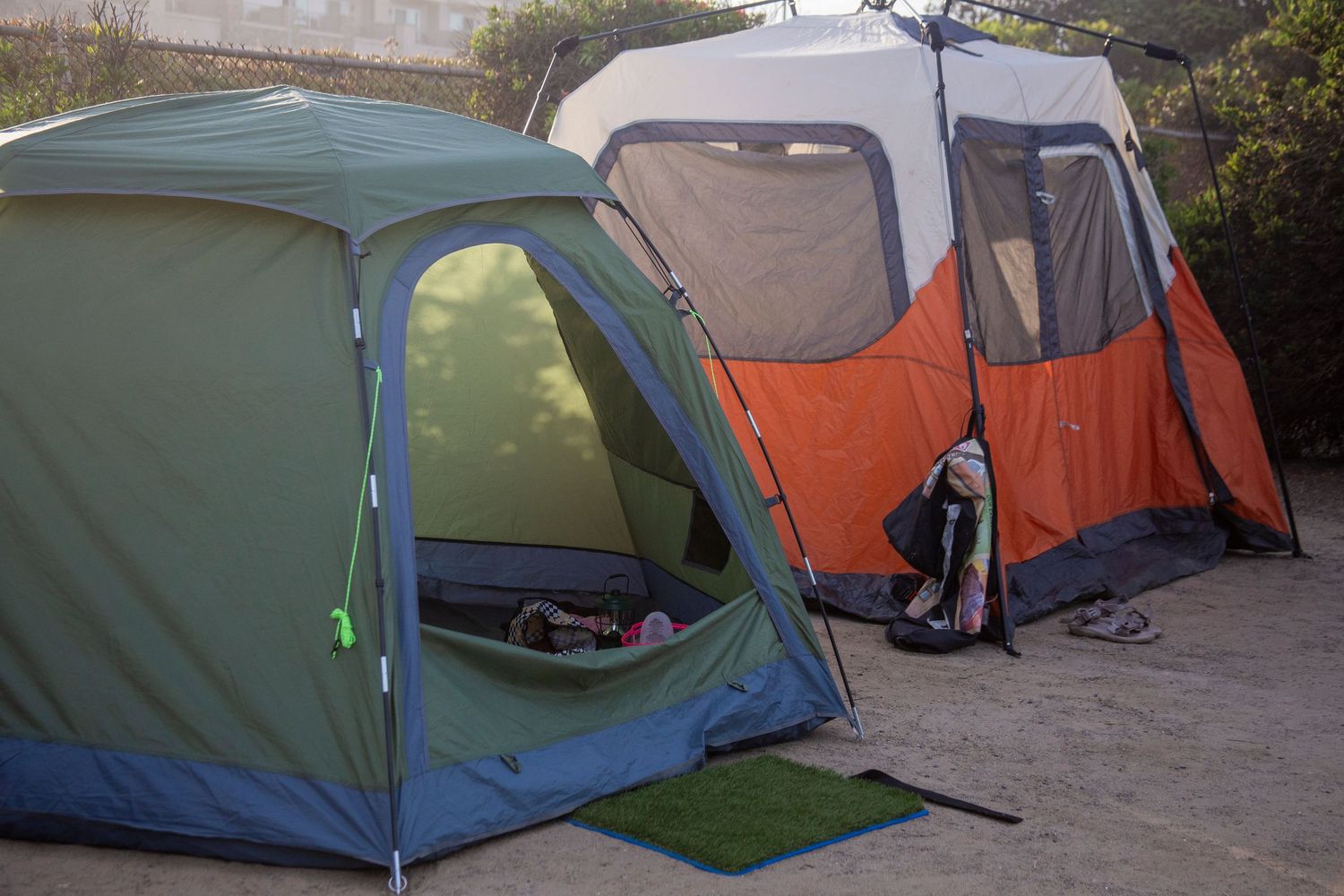 Multiple camping tents in various colors like blue, green and orange set up in an outdoor area on a surf trip.