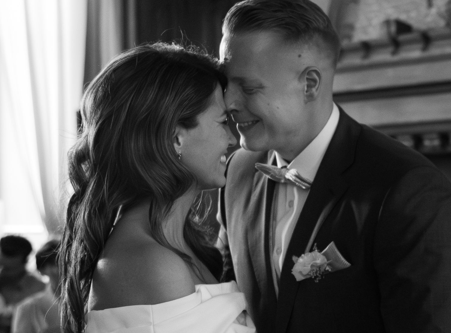 Black and white wedding photo of bride and groom sharing an intimate moment, smiling close together.