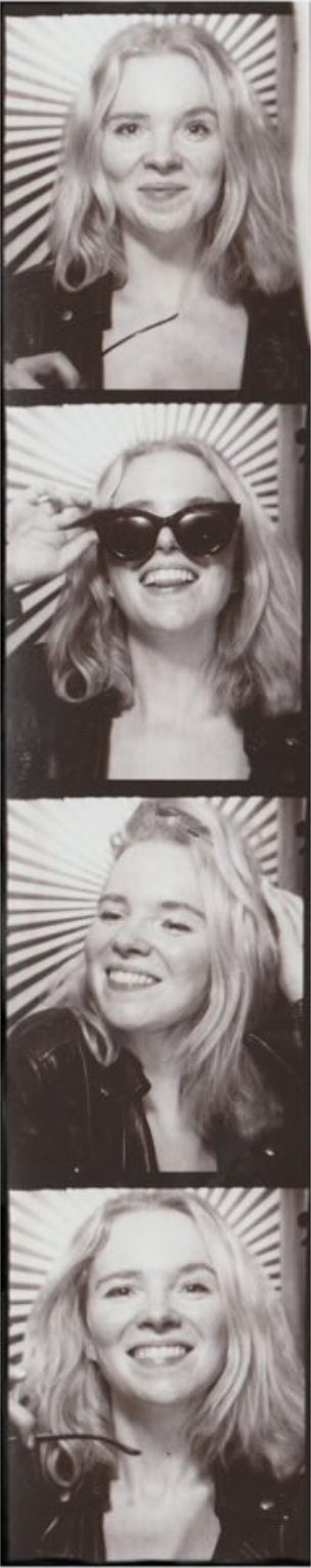 Black and white photo booth strip of a smiling blonde woman posing in four frames, one wearing cat-eye sunglasses.