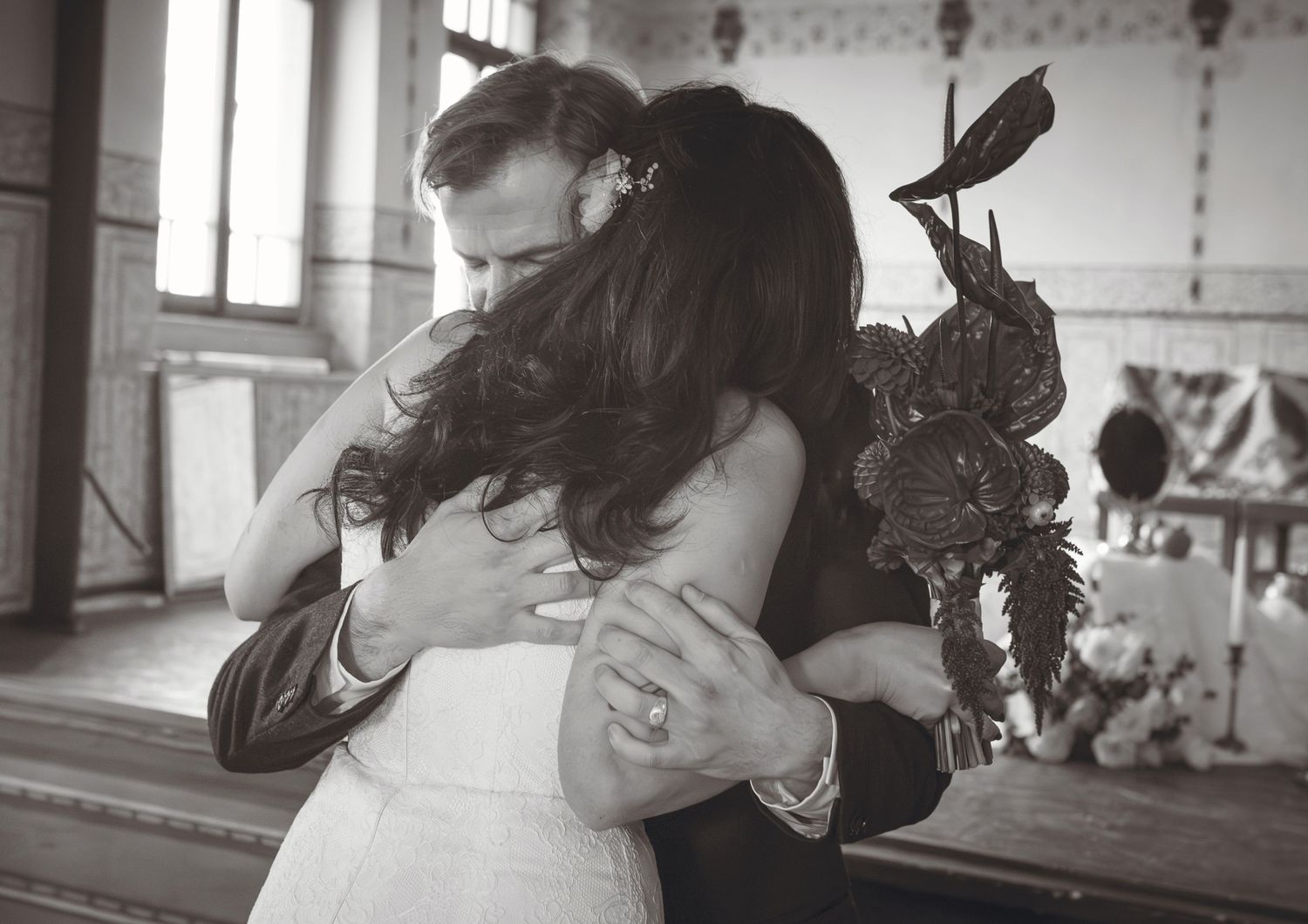 Black and white photo of a bride and groom sharing a tender embrace on their wedding day.