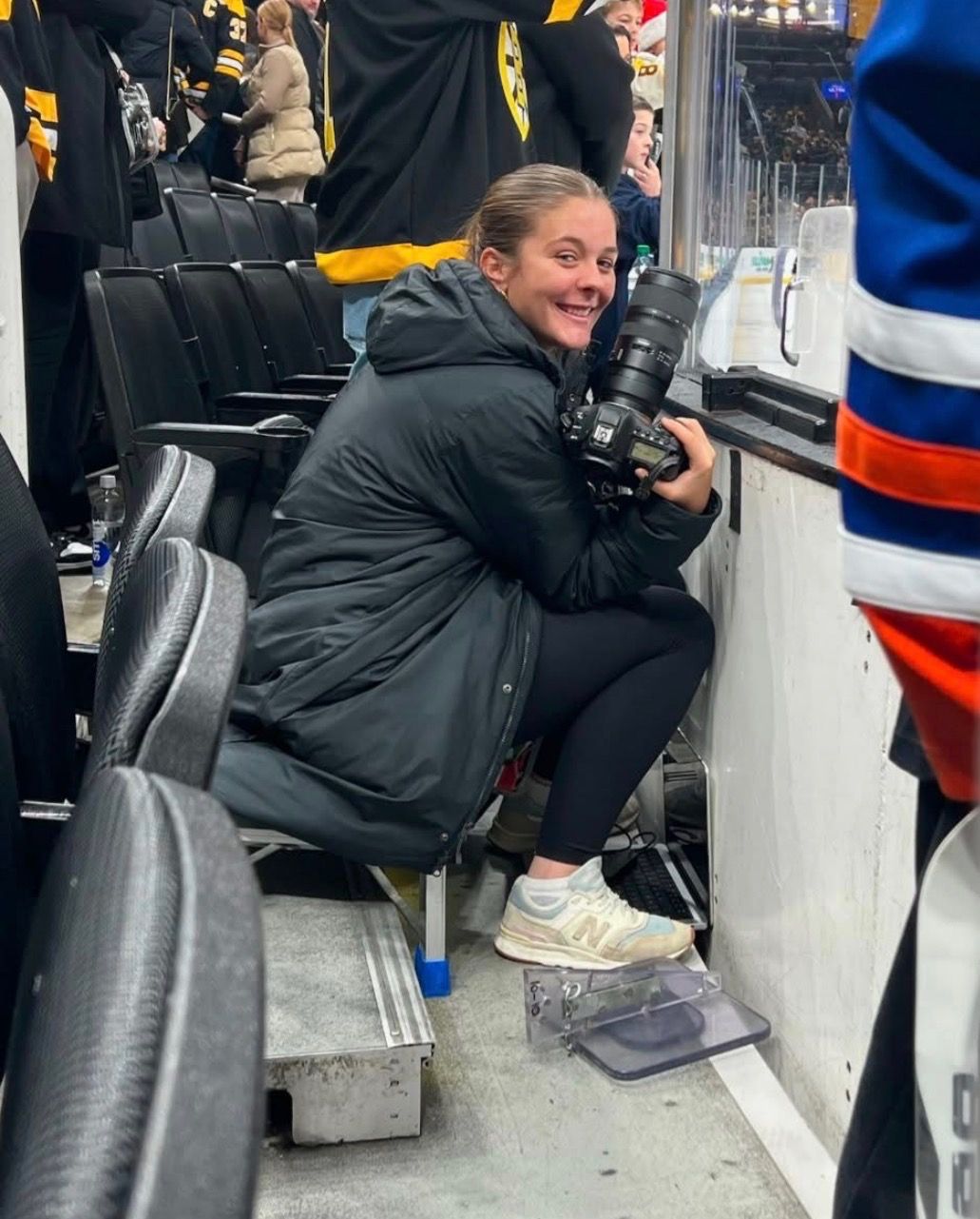 Sports photographer with professional camera equipment works from sideline position.
