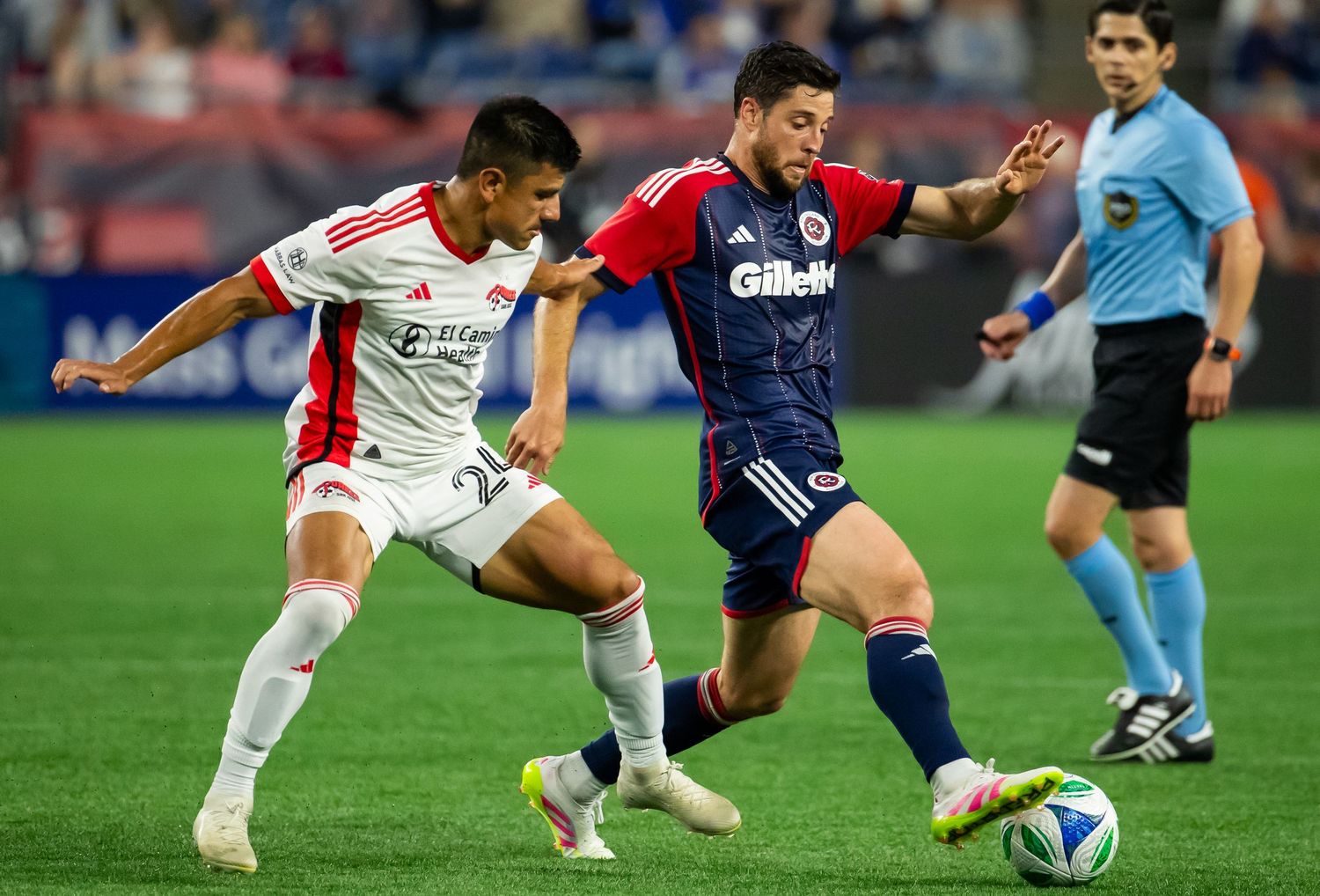 Soccer players from opposing teams battle for ball possession during an intense match.
