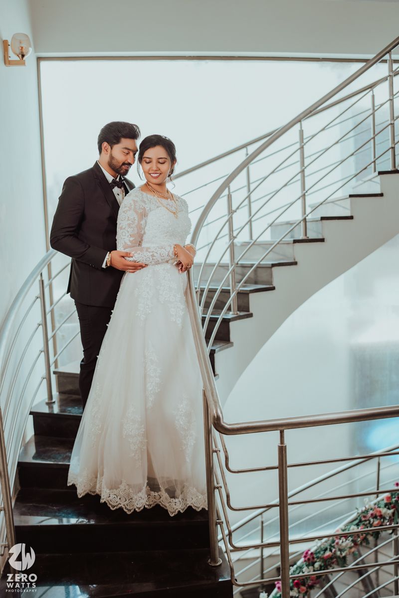Romantic wedding photoshoot on modern staircase featuring elegant white gown and dark suit.