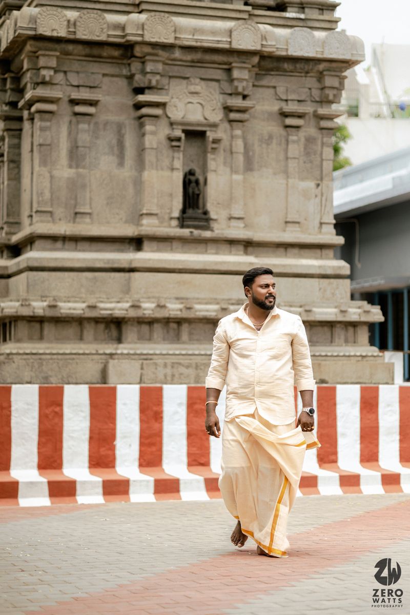 Traditional South Indian temple architecture with red and white striped walls and stone pillars creates a cultural backdrop.