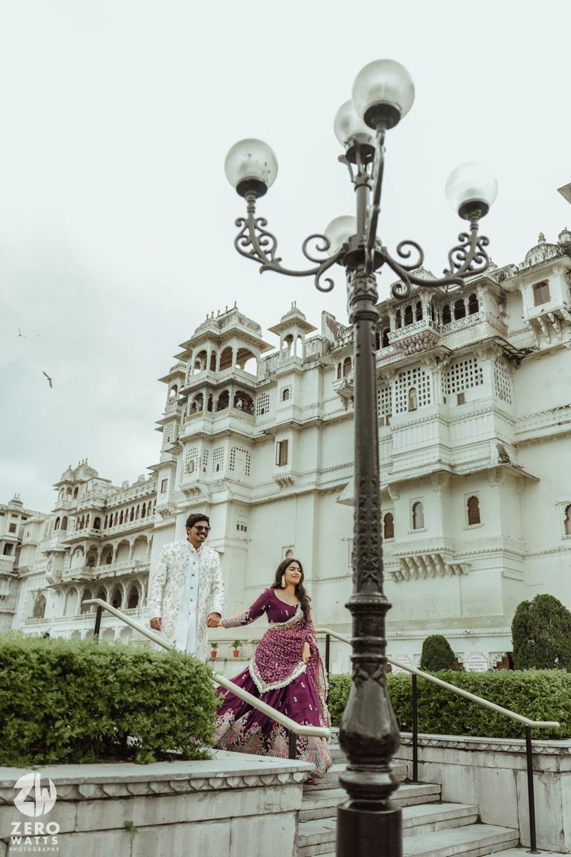 Romantic couple portrait at Udaipur City Palace with ornate architecture and vintage lamp post.