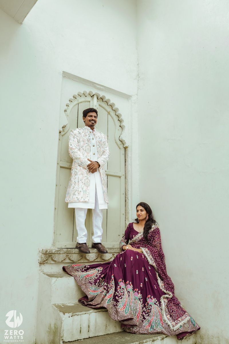 Romantic couple photoshoot featuring traditional Indian attire with white and purple outfits against a minimalist setting.