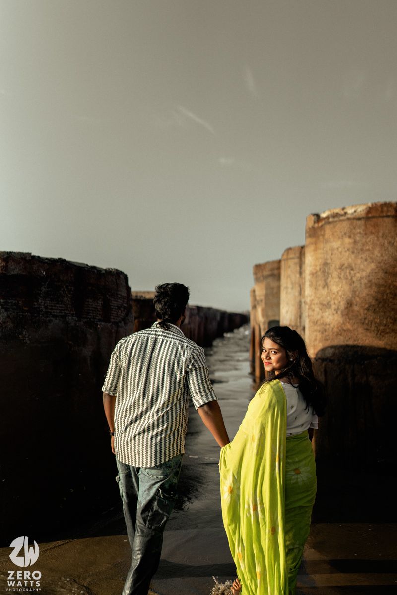 Two people in casual attire walk along ancient stone fortress walls at sunset creating dramatic silhouettes.