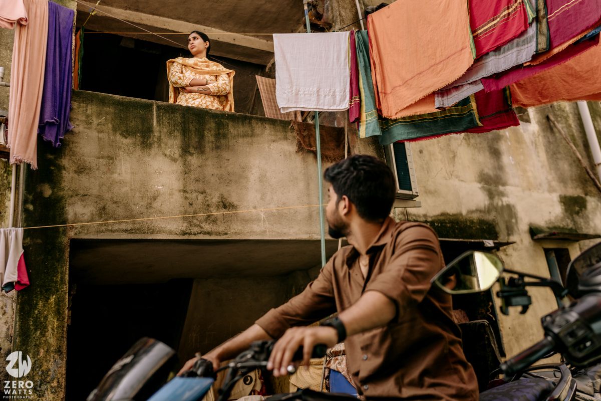 Colorful clothing and textiles hang on clotheslines in an urban alleyway with laundry drying in the sunlight.