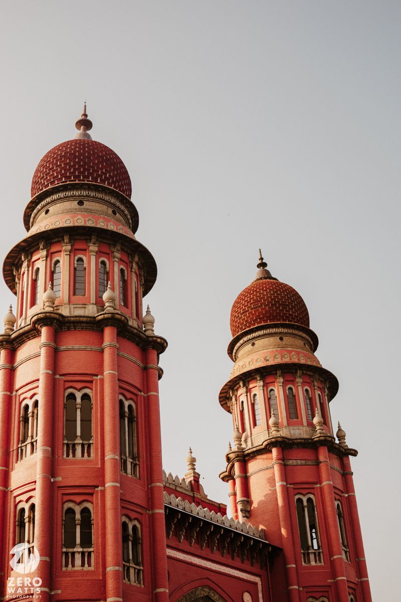 Ornate red domed towers and turrets of historic Indian colonial architecture against grey sky.