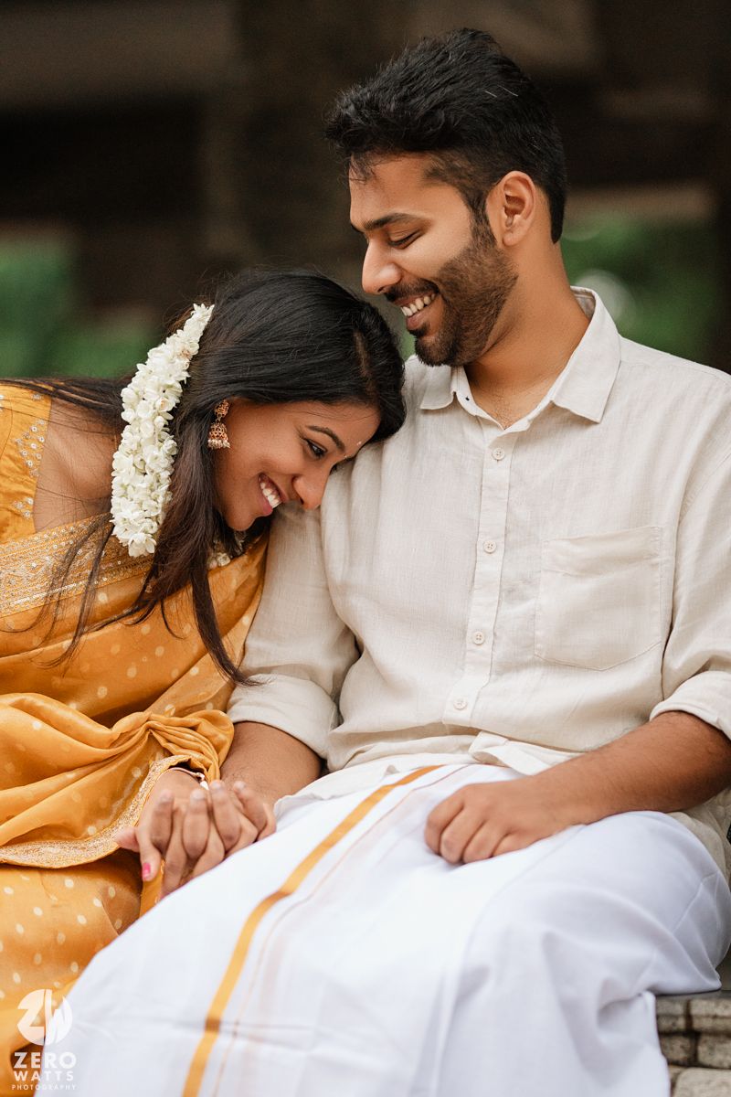 A couple in traditional Kerala attire share intimate moments while sitting together outdoors.