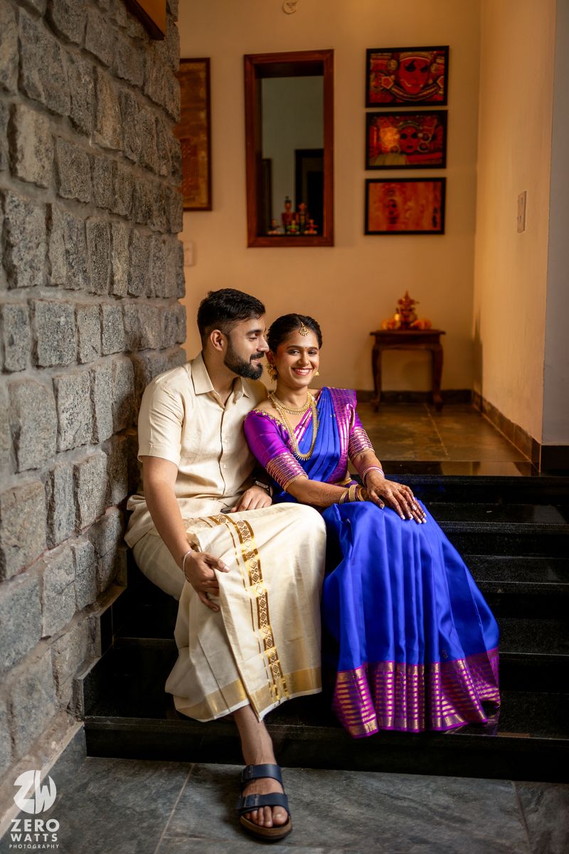 A couple sits intimately on stone steps in an indoor setting with artwork on the walls.