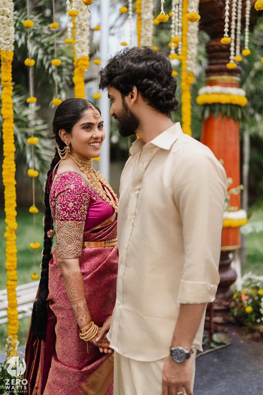 Wedding couple in traditional South Indian attire under yellow marigold flower decorations.