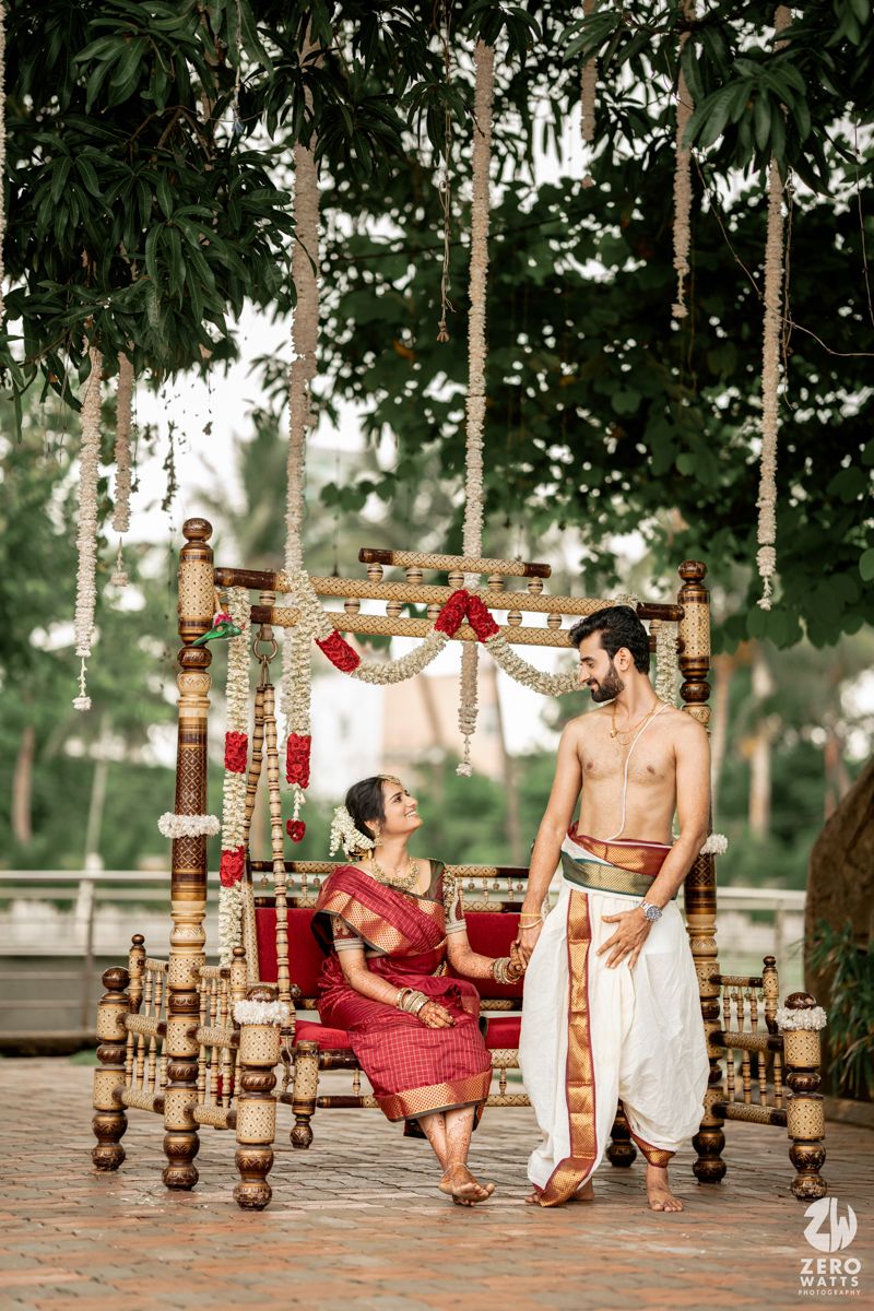 Ornate wooden swing decorated with red and gold accents in a lush garden setting.