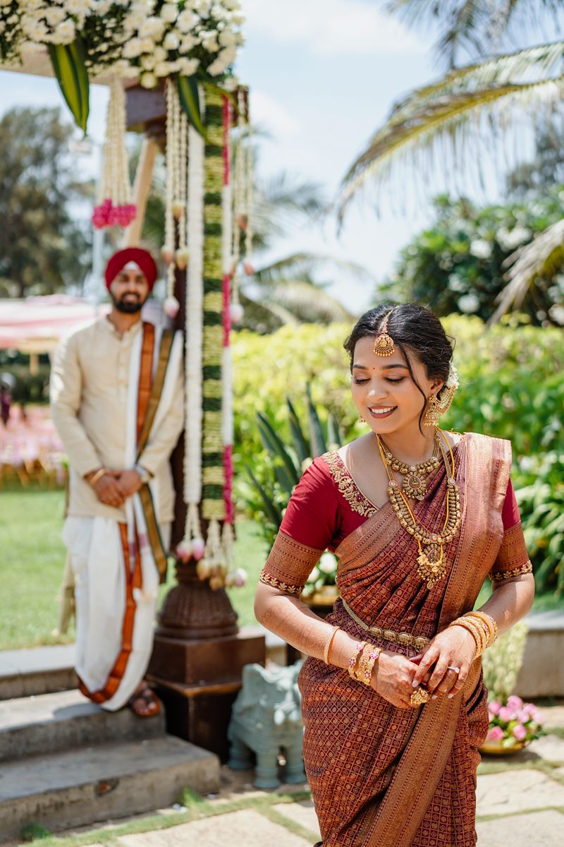Outdoor wedding celebration with traditional Indian decor and palm trees in the background.