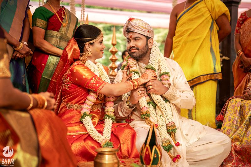 Bride and groom in traditional South Indian wedding attire perform sacred rituals at decorated mandap.