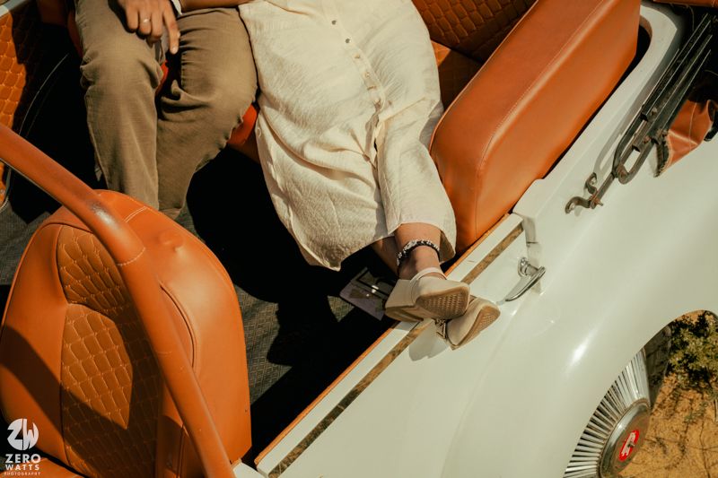 Close-up details of an orange and white vintage car with people seated inside.