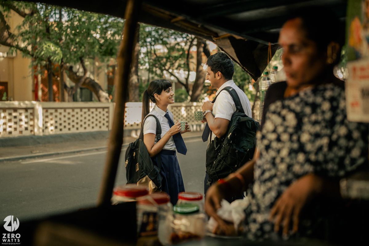 Students gathered under shady trees on a sunny afternoon at school.