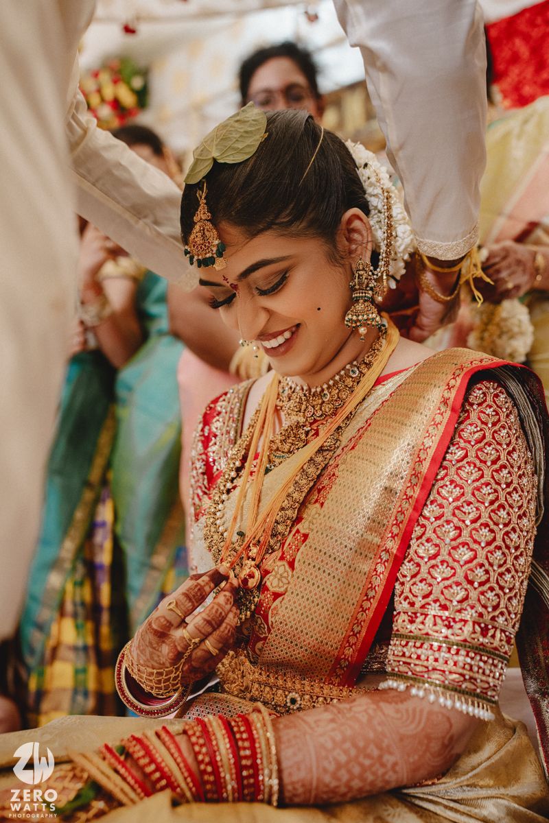Traditional Indian bride in red and gold attire with ornate jewelry shown in a series of candid moments during ceremony.
