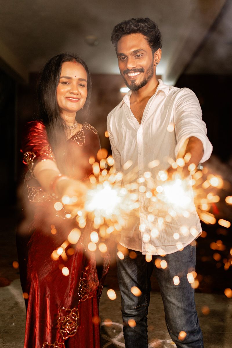 A couple holds sparklers creating magical light trails against a dark background in a series of romantic shots.