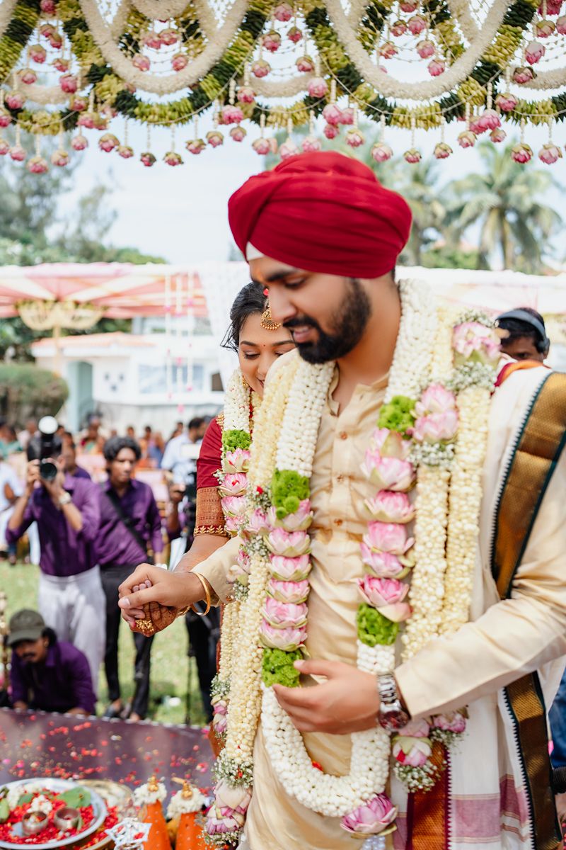Traditional wedding ceremony with floral garlands and decorative elements under ornate canopy.