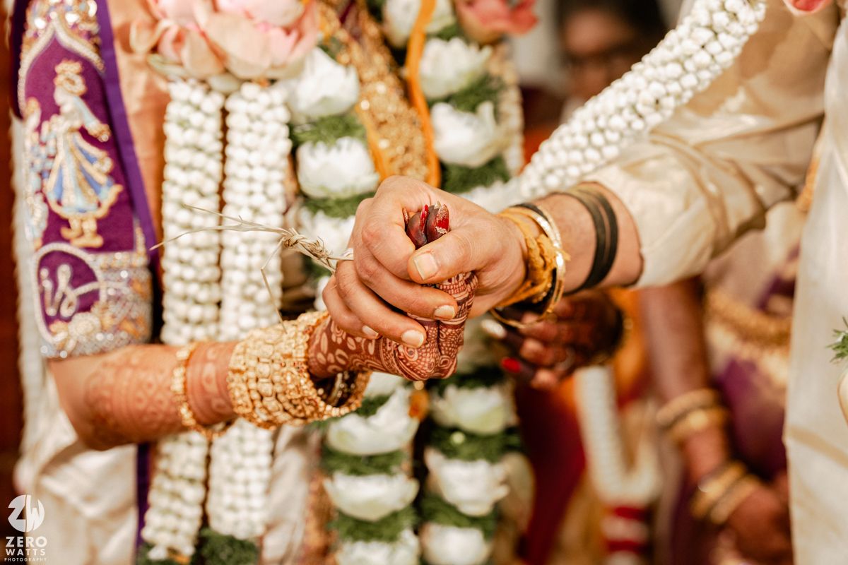 Hands adorned with henna and bangles during traditional wedding ceremony.