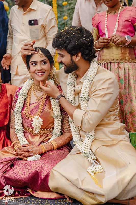 Traditional South Indian wedding ceremony with couples wearing garlands and cream colored outfits.