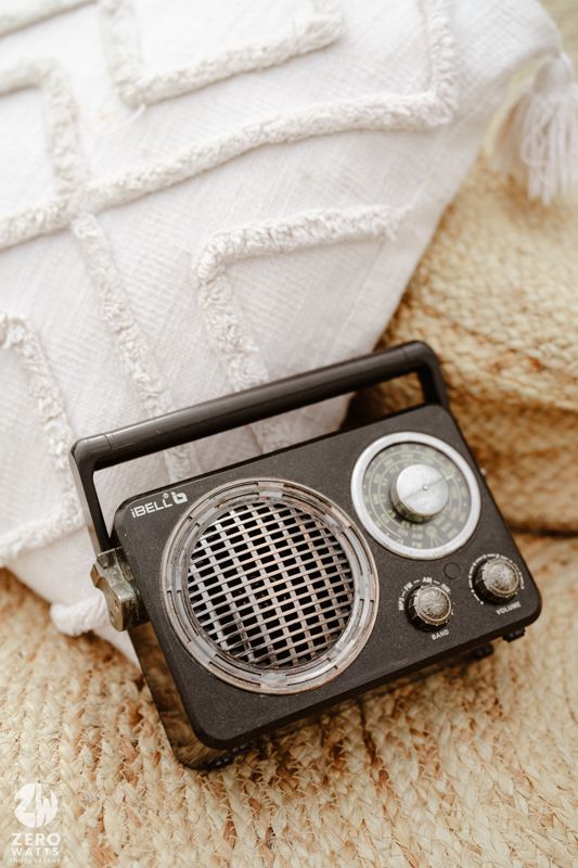 Vintage black portable radio with metal grille and control knobs sits on textured surface.