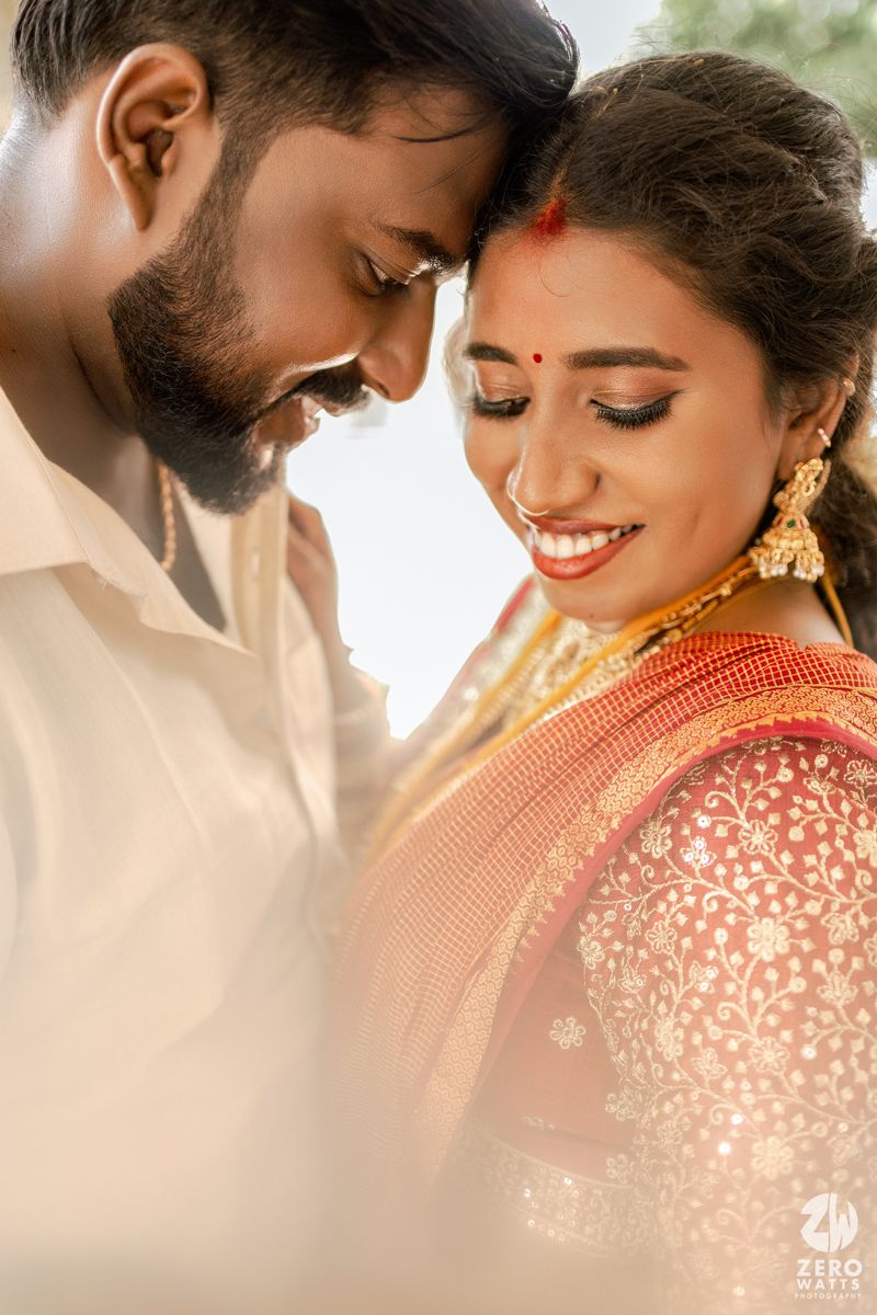 A romantic couple in traditional Indian wedding attire share an intimate moment in soft lighting.