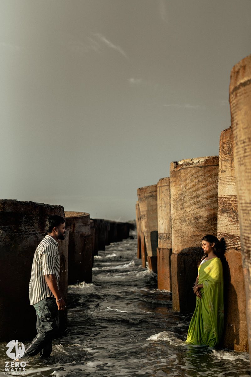 Dramatic seaside photo series shows two people posing between stone pillars as waves crash against a rocky shore.