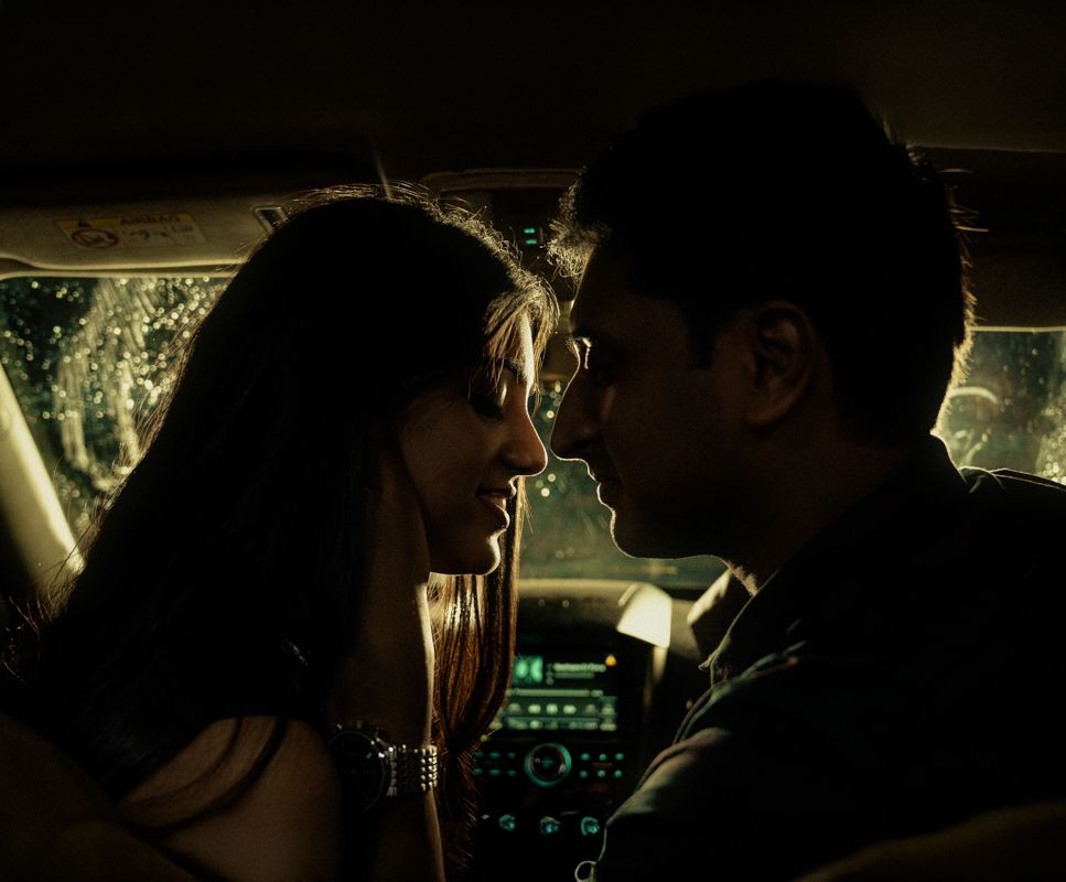 Romantic silhouette of a couple in close proximity inside a vehicle at night.