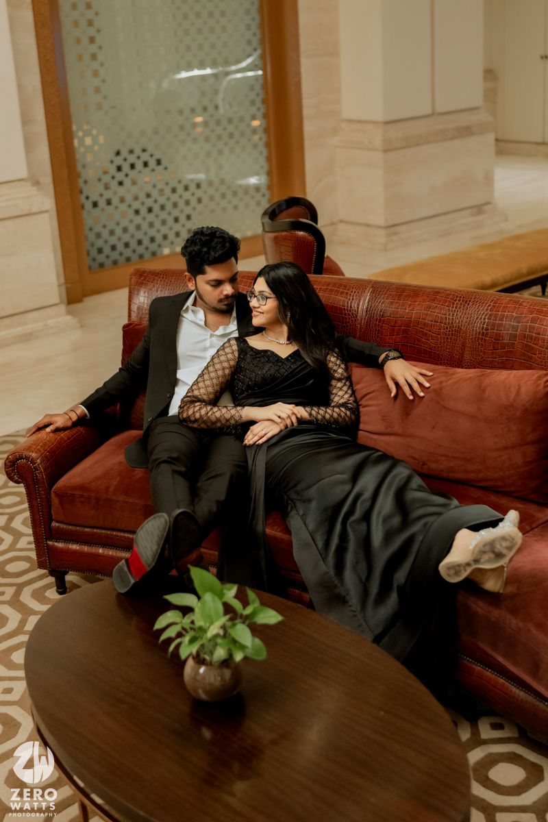 A couple relaxes together on a brown leather couch in an elegant room with patterned decor.