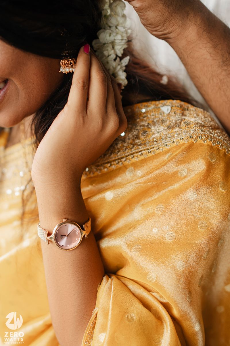 Close-up detail of a golden silk sari with delicate embroidery and jewelry accents.