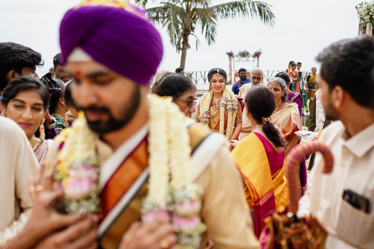 Festive crowd gathered at an outdoor Indian wedding ceremony with vibrant purple and traditional attire.