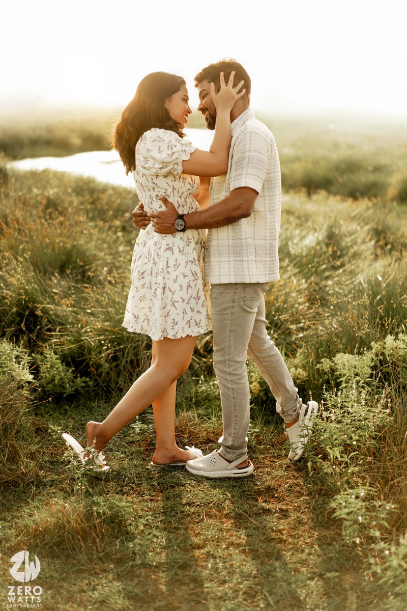 Couple in casual attire dancing together in a sunlit meadow with wildflowers during golden hour.