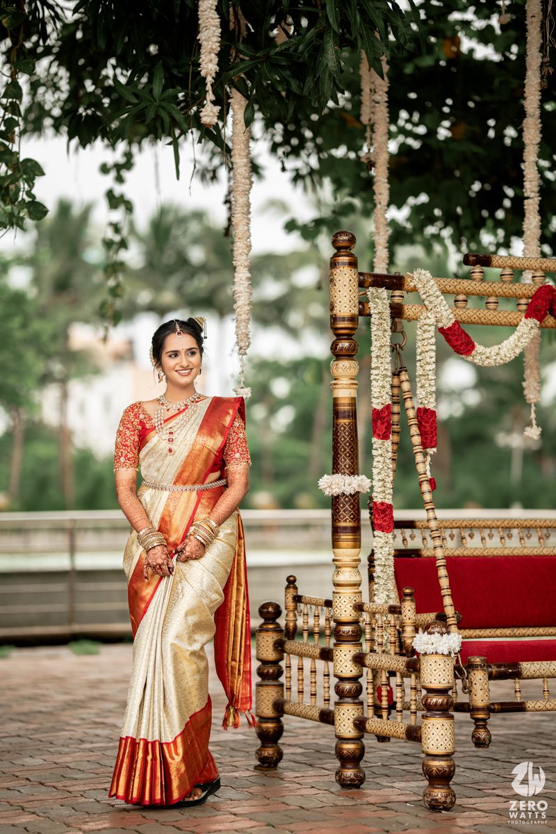Traditional South Indian wedding mandap decorated with wooden pillars and floral garlands in a garden setting.